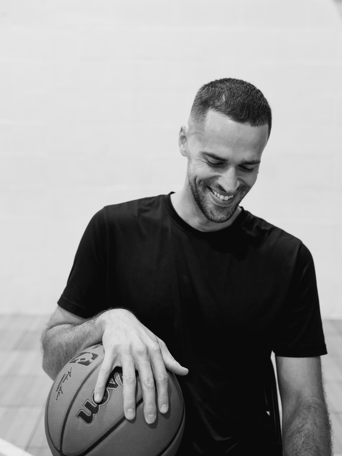 Coach Carlos seated with a basketball on an outdoor court